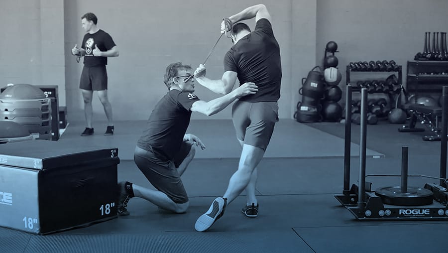 Coach assisting an athlete through a cable and band movement